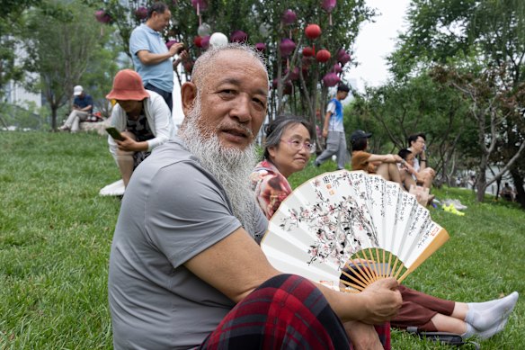 Calligraphy artist Qu Pu, 65, watches the festival at Beijing&rsquo;s Grand Canal, his handpainted fan keeping him cool in the summer heat. 