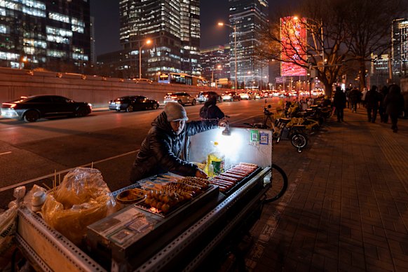 A snack food vendor grills sausages in Beijing’s central business district. With China’s economy still reeling from its property market collapse, consumers are spending less and many people have seen their wages stagnate or decline. 
