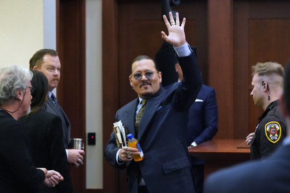 Johnny Depp gestures to the gallery in the courtroom as he leaves for a break during his court case against Amber Heard.
