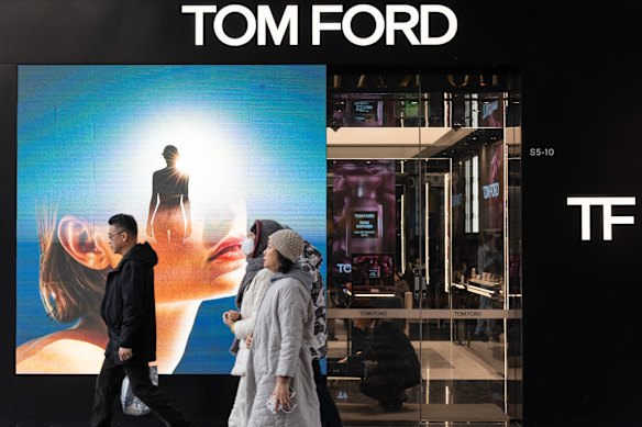 人々は、BeijngのSanlitunショッピング地区にあるアメリカの高級ブランドであるTom Fordの店を通り過ぎます。