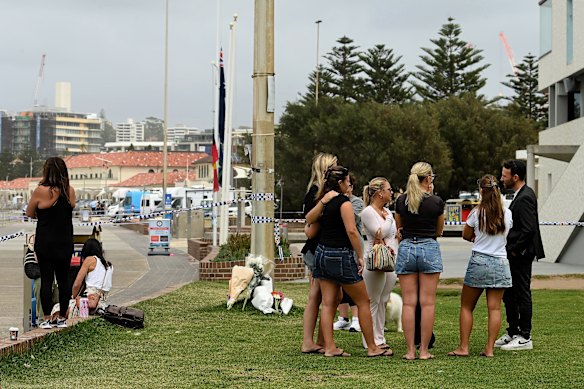 Next to flowers and police tape, Rabbi Yossi Friedman (right) talks with a group of women at the northern end of Bondi Beach.