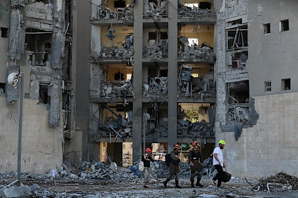 Emergency workers escort residents to their apartment building that was hit by an Iranian ballistic missile in Beersheba on Tuesday.