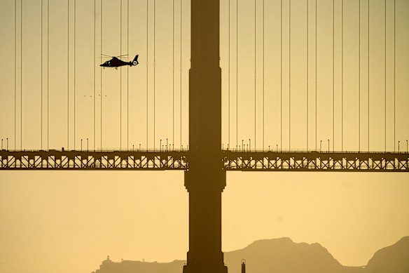 A helicopter flies past the Golden Gate Bridge while searching for missing victims after a boat accident near Alcatraz Island off San Francisco.