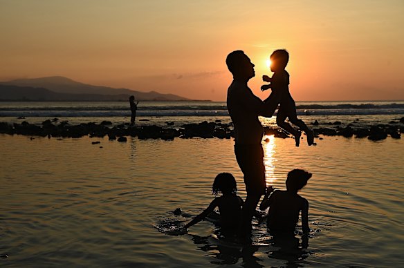 A family plays as the sun sets at the foreshore in Dili.
