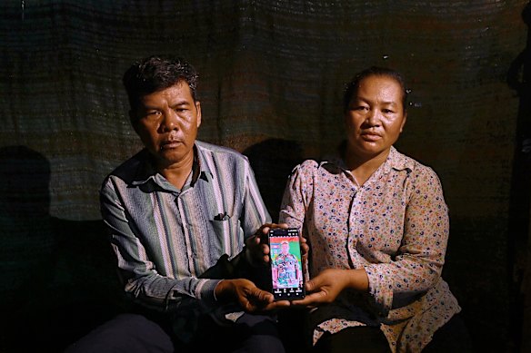 At their home in Sret East village, Vowung Vy (left) and Trip Huon (right), hold a photo of their son, Vy Chhorvon.