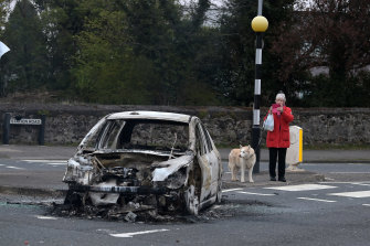 Une femme prend une photo d'une voiture incendiée à Cloughfern, à la suite de violences loyalistes à Belfast, en Irlande du Nord.