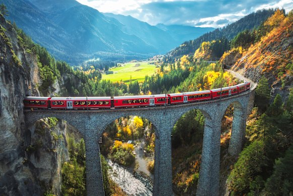  A passenger train on the famous Bernina Express route crosses an historic viaduct.