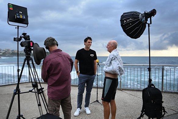 Australian captain Pat Cummins talks with friend Ian Muddle at Bronte Beach before a live cross to a TV breakfast show.