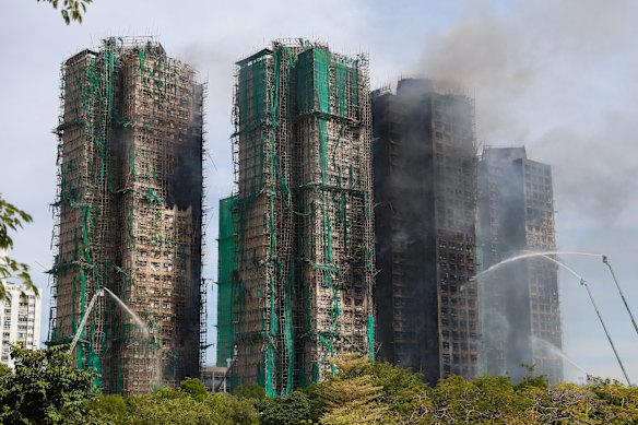 Smoke continues to drift from the blackened husks of the Wang Fuk apartments.