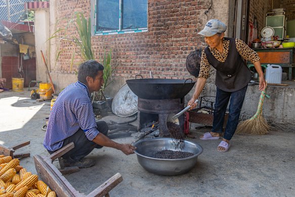 Li Jinrong’s wife removes freshly roasted coffee beans from the hot cast-iron wok.