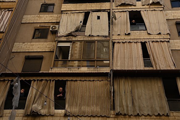 Residents look across the narrow street at an apartment building in the Aisha Bakkar area in central Beirut that was hit by an Israeli airstrike, killing four people. 