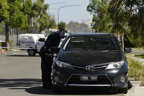 A NSW police forensic officer inspects the car with Victorian number plates.