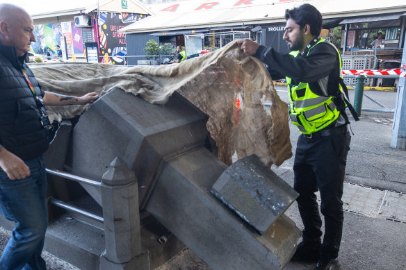 A security guard covers up the destroyed monument to John Batman at Queen Victoria Market.