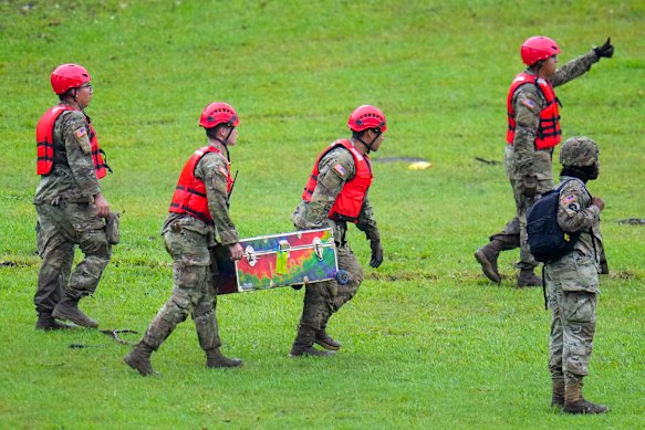 Military personnel carry a child’s camp trunk salvaged downriver from Camp Mystic along the Guadalupe River.