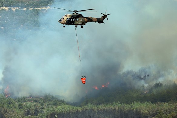A helicopter sprays water to extinguish a fire in Seferihisar, near Izmir, Turkey.