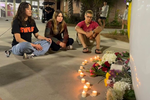 People sit in front of a makeshift memorial outside the student union office after the campus shooting at Florida State University last year.