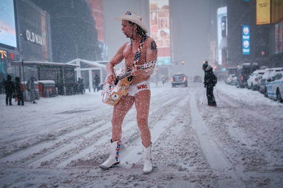 The Naked Cowboy performs under the snow in New York’s Times Square.