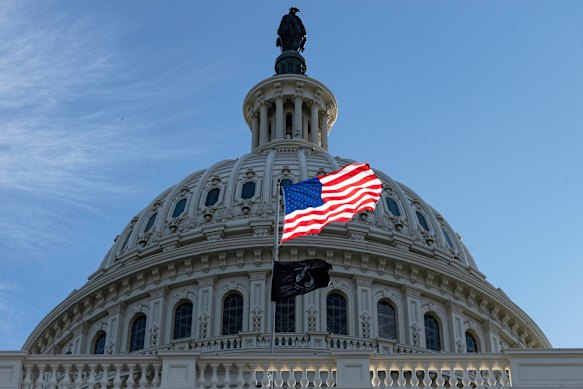 The American flag over the Capitol is illuminated by the early morning light on the first day of a government shutdown in Washington. 