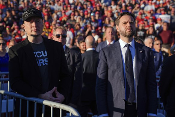 Elon Musk and JD Vance listen to Donald Trump at a campaign rally in October 2024.