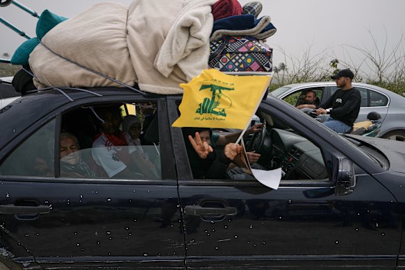 A displaced woman waves a Hezbollah flag near Tyre, southern Lebanon.