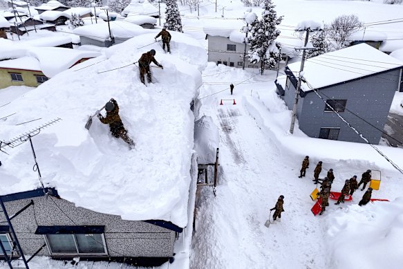 Members of the Japan’s Ground Self-Defence Force removing snow from a house’s roof in Aomori City.