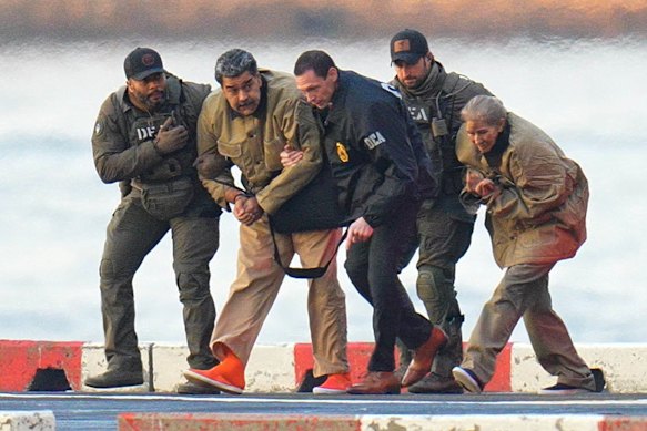 Nicol&aacute;s Maduro and Cilia Flores (right) are handcuffed at a New York heliport before their transfer to the court.