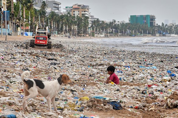 A ragpicker boy searches for recyclable materials among plastic and other waste washed ashore by high tide on the Juhu Beach on the Arabian Sea coast in Mumbai, India.