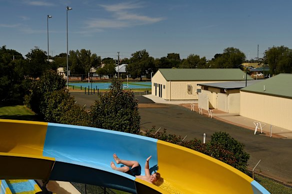 Max Kennedy, 12, waves as he goes down the water slide at the War Memorial Pool in Nyngan.