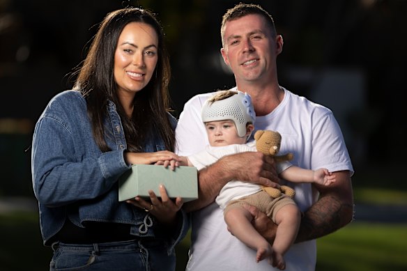 Maddison and Luke Waldron with their son, Kai. The family received an “angel box” of clothes made by volunteers after Kai’s twin, Teddy, was stillborn. The box Maddison is holding contains Teddy’s ashes.