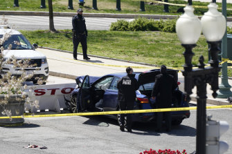 La police se tient près d'une voiture qui s'est écrasée contre une barrière près du Capitole américain.