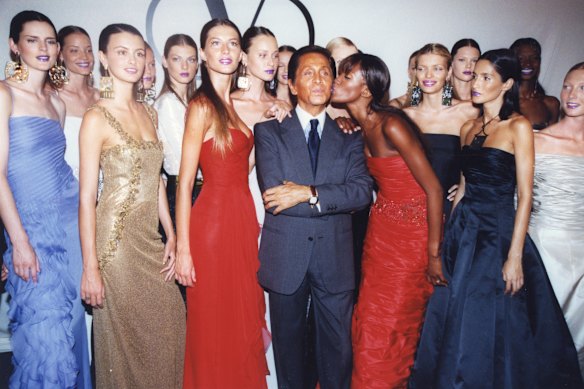 Valentino receiving a kiss from Naomi Campbell following his haute couture show at paris Fashion Week in July, 1999.