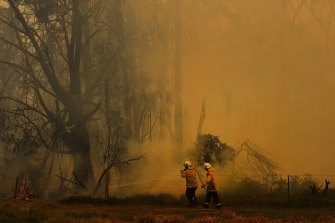 NSW RFS firefighters are surrounded by smoke as they work on battling a fire at Tahmoor, NSW.