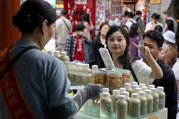 People queue to buy douzhi at the Yin San Douzhi store in the Nanluoguxiang shopping street in Beijing.
