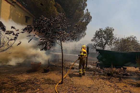 A firefighter attempts to extinguish a house fire caused by wildfire in Spain.