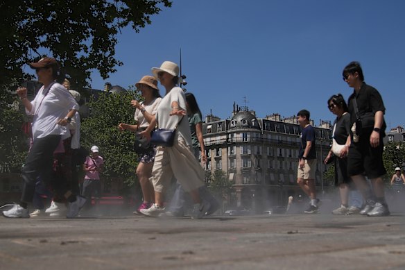 Tourists walk through a water mister in Paris on Monday.