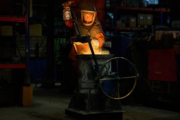 A furnace worker stirs molten metal as part of the process to create BAFTA masks at FSE Foundry in Braintree, England.