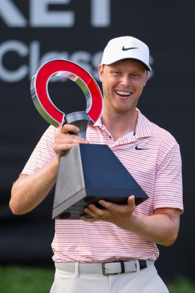 Cameron Davis celebrates with the Rocket Mortgage Classic trophy successful  Detroit.