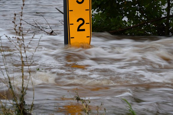 A flood gauge marks the height of water flowing over a farm-to-market road near Kerrville, Texas, on Friday.