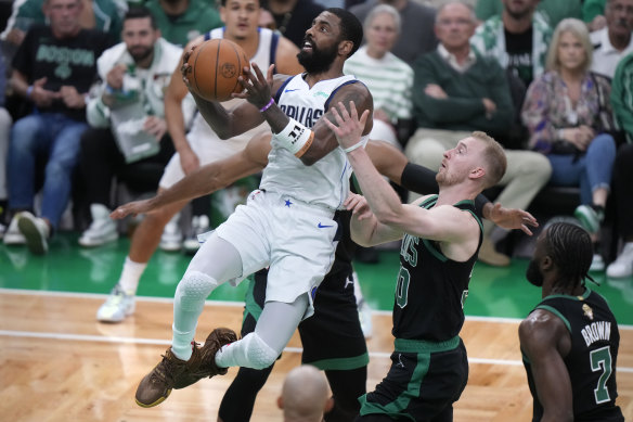Dallas Mavericks guard Kyrie Irving, front left, drives to the basket past Boston Celtics forward Sam Hauser.