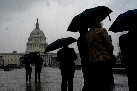Visitors carrying umbrellas during heavy rain walk past the U.S. Capitol on Capitol Hill in Washington.