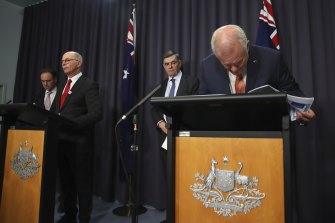 Greg Hunt, le professeur Paul Kelly et le professeur Brendan Murphy avec le premier ministre Scott Morrison examinant de plus près ses notes lors d'une conférence de presse jeudi soir.