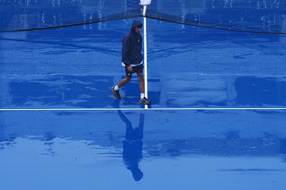 A crew member walks across the court at Grandstand stadium during a rain delay at the U.S. Open tennis championships.
