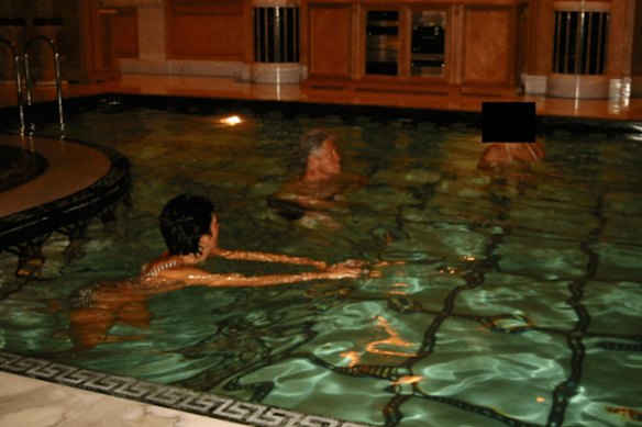 This undated, redacted photo released by the US Department of Justice shows Ghislaine Maxwell and former President Bill Clinton swimming with an unknown person.