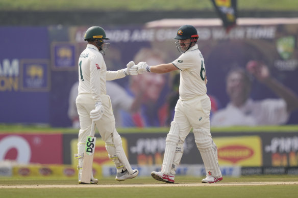 Australia’s Travis Head, right, bumps fists with Usman Khawaja after hitting a four.