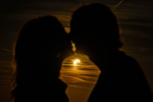 A couple kissees during a partial solar eclipse at the former airport Tempelhof in Berlin, Germany.
