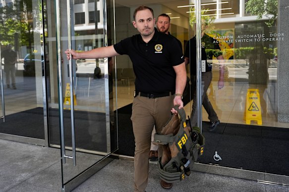 FBI agents walk out the front entrance of ex-Trump national security adviser John Bolton’s Washington office.