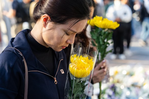 A mourner holding a flower near the site to mourn the victims of Hong Kong’s deadly apartment fires.