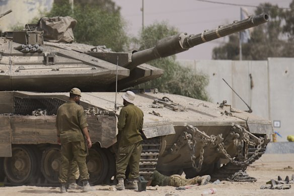 Israeli soldiers work on a tank at a staging area near the border with the Gaza Strip, in southern Israel on Tuesday.