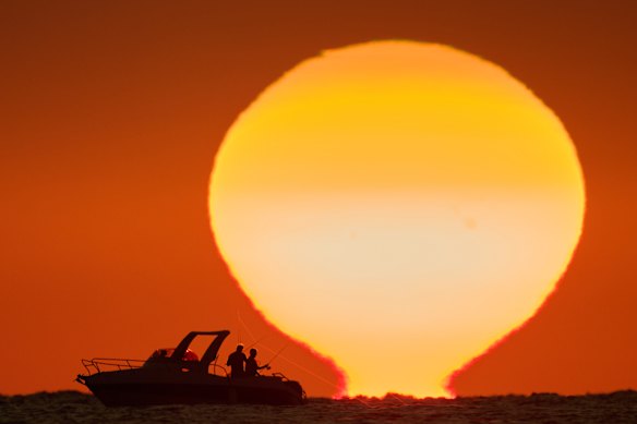 Fishermen are silhouetted aboard a boat as the sun sets over the Mediterranean Sea in Beirut, Lebanon.