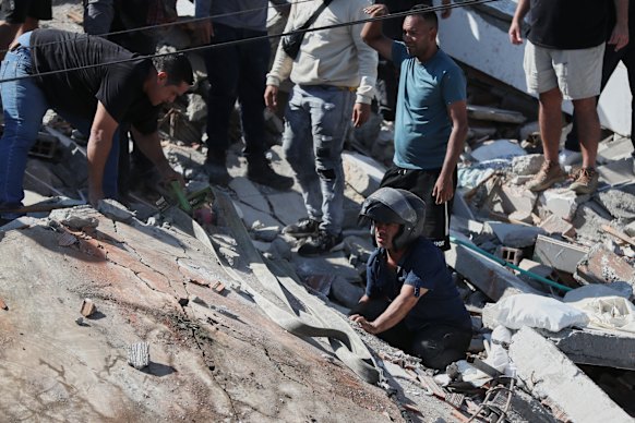 A rescue worker searches under a roadway for survivors.